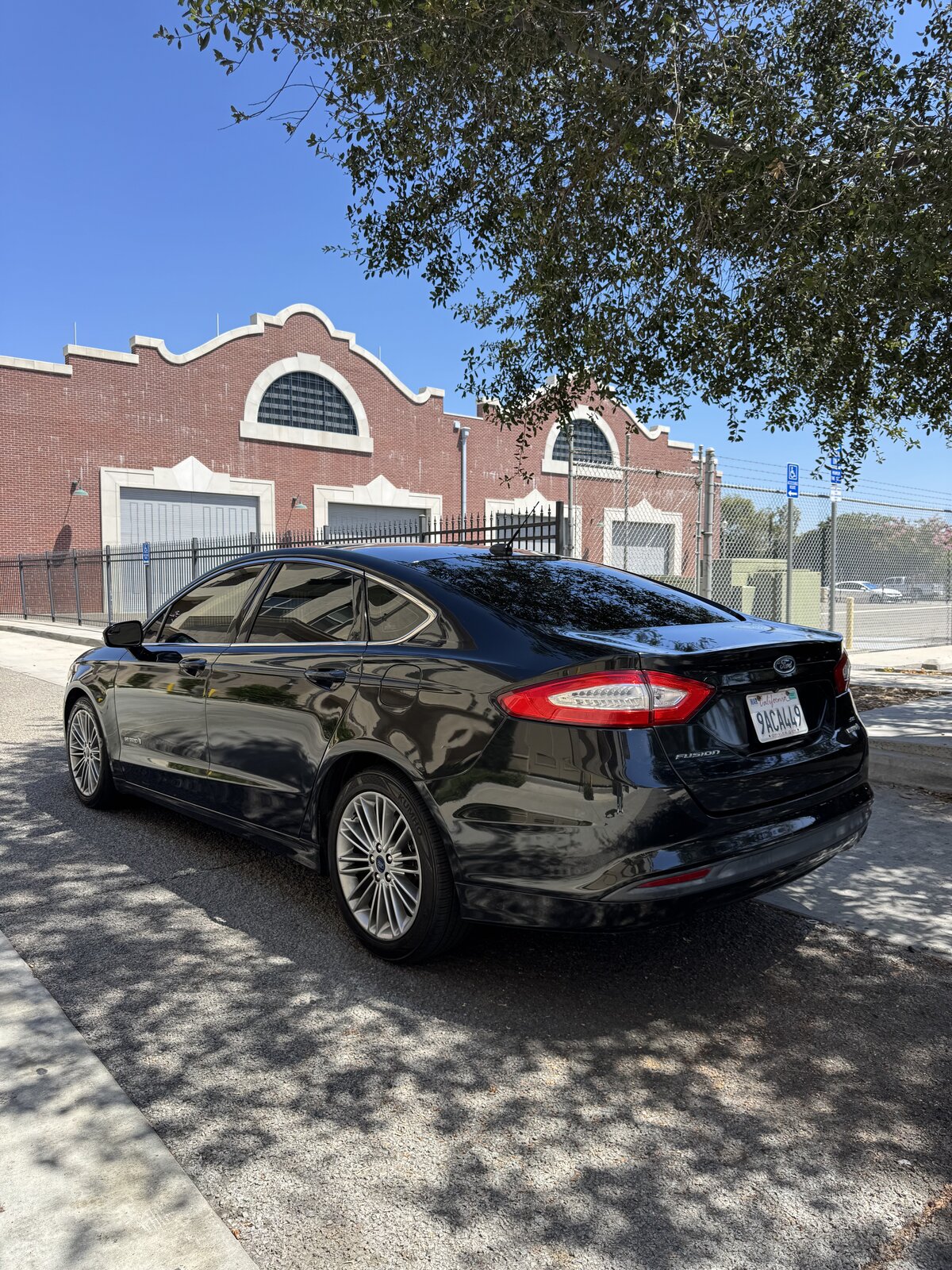Black 2014 Ford Fusion Hybrid rear driver-side three-quarter view